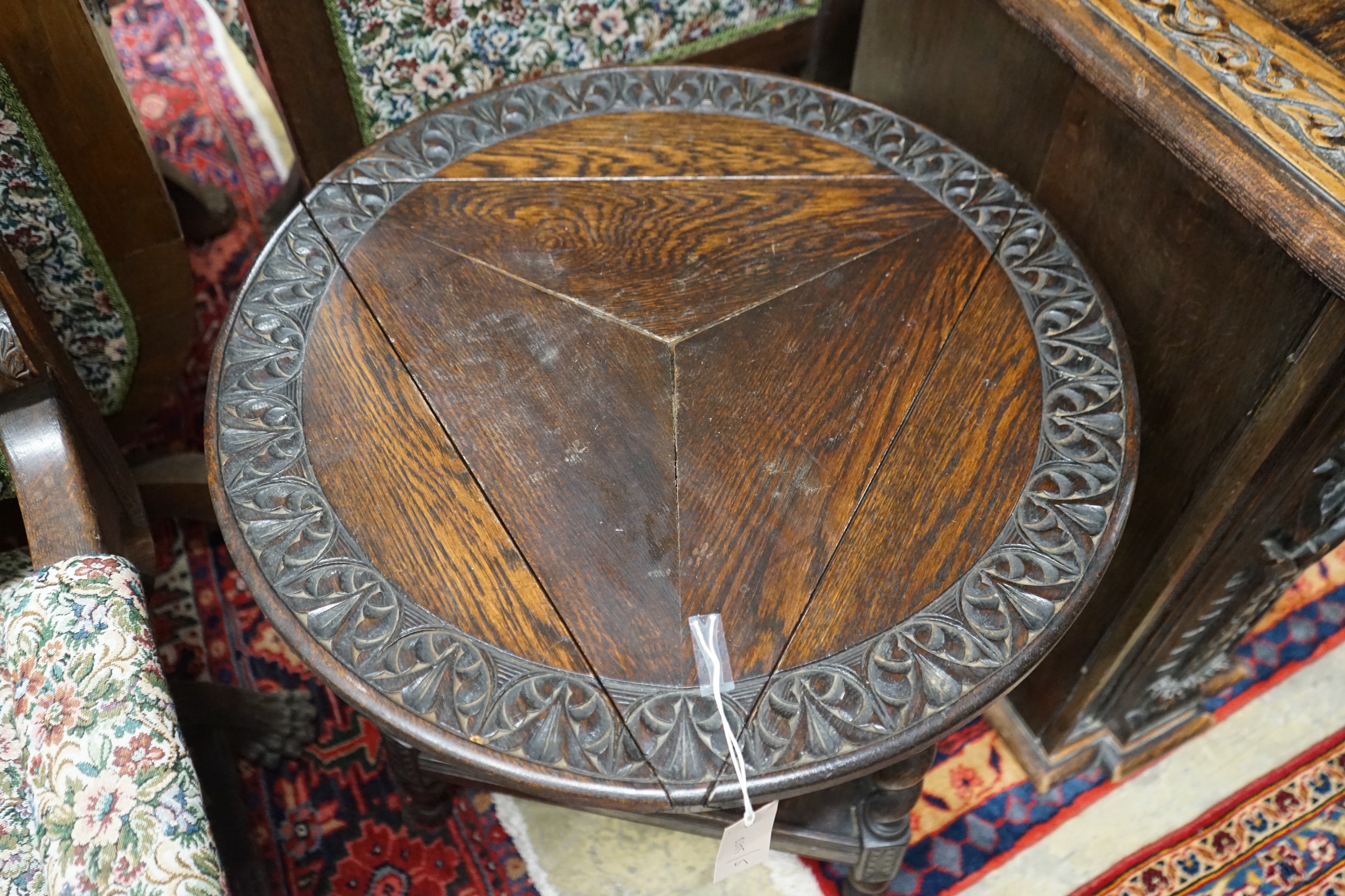 A 1920's circular oak drop flap two tier occasional table, diameter 61cm, height 69cm